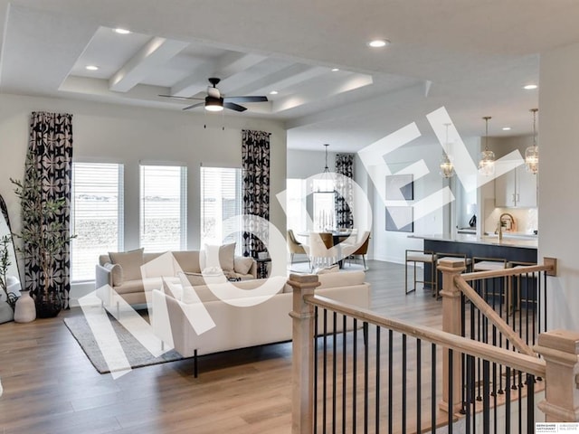 living room featuring beamed ceiling, ceiling fan with notable chandelier, and hardwood / wood-style flooring