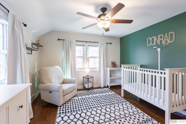 bedroom featuring lofted ceiling, ceiling fan, dark hardwood / wood-style floors, and a crib