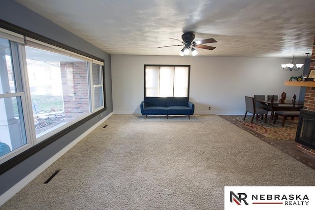 sitting room with ceiling fan with notable chandelier and carpet