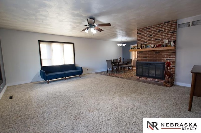 living room featuring ceiling fan with notable chandelier, a fireplace, and carpet