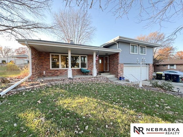 tri-level home featuring a porch, a garage, and a front lawn