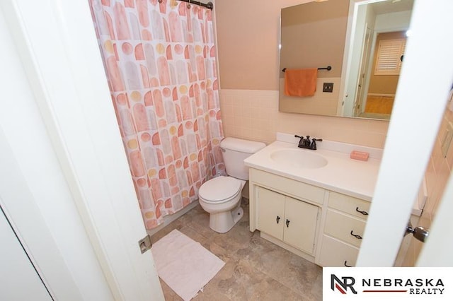 bathroom with tile walls, vanity, and toilet