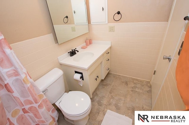 bathroom with tile walls, vanity, and toilet