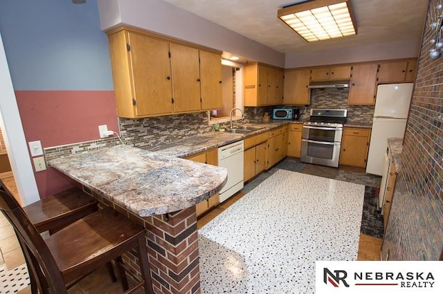 kitchen with sink, backsplash, a kitchen bar, kitchen peninsula, and stainless steel appliances