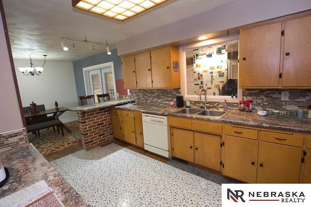 kitchen featuring white dishwasher, a chandelier, sink, and backsplash