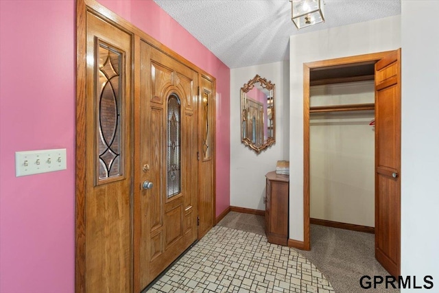 carpeted foyer with a textured ceiling