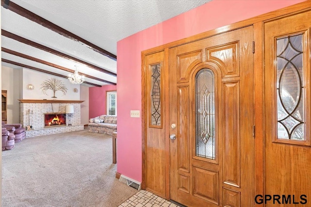 entryway featuring beam ceiling, light carpet, a fireplace, and a textured ceiling