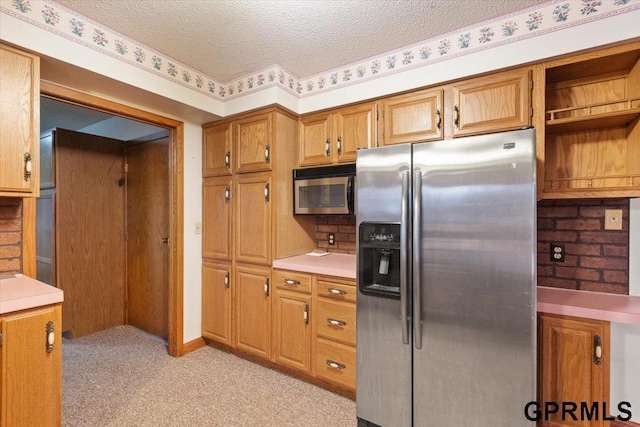 kitchen featuring light colored carpet, stainless steel appliances, and a textured ceiling