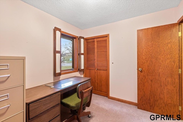 unfurnished office featuring a textured ceiling and light colored carpet