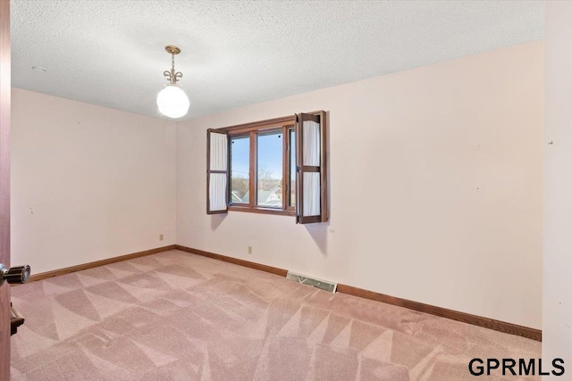 spare room with a textured ceiling and light colored carpet