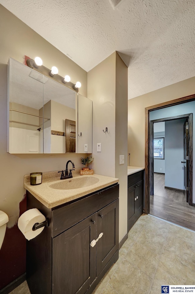 bathroom with vanity, hardwood / wood-style floors, and a textured ceiling