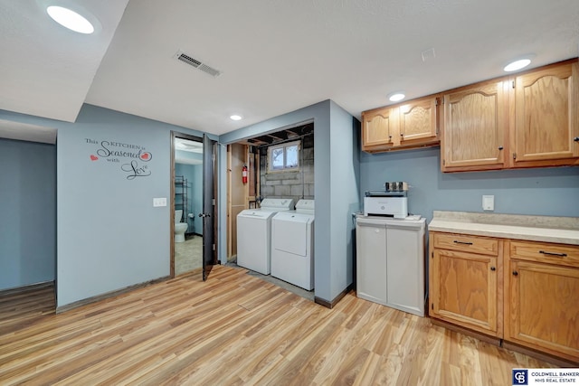 washroom with separate washer and dryer and light hardwood / wood-style flooring