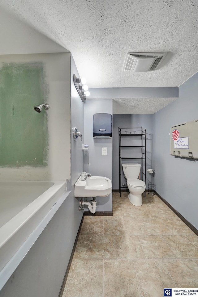 bathroom with a textured ceiling, toilet, and sink