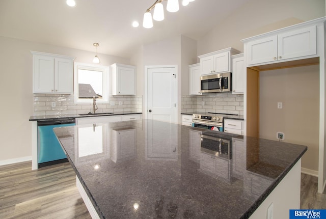 kitchen with stainless steel appliances, white cabinetry, sink, and decorative light fixtures