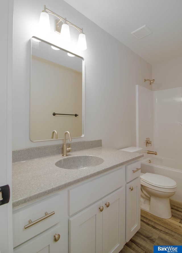 full bathroom with vanity, hardwood / wood-style floors, shower / bathtub combination, and toilet