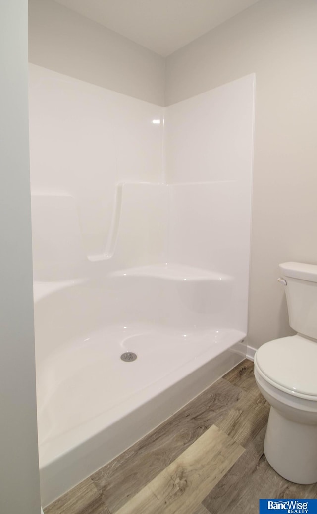 bathroom with hardwood / wood-style flooring, a shower, and toilet