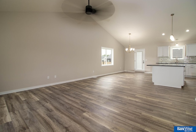 unfurnished living room featuring lofted ceiling, dark wood-type flooring, ceiling fan with notable chandelier, and sink