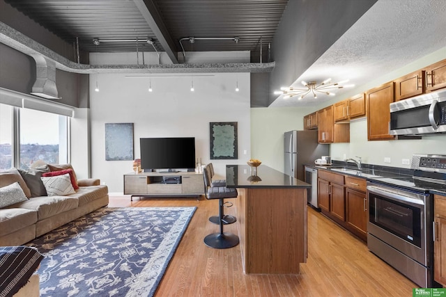 kitchen with a center island, a breakfast bar area, appliances with stainless steel finishes, and light hardwood / wood-style flooring