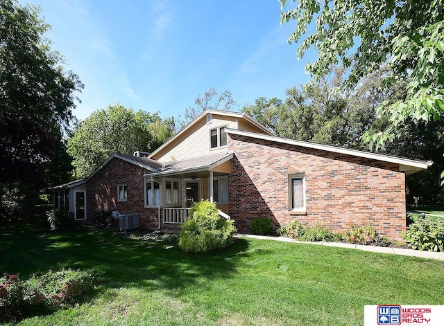 view of front of home with central air condition unit, a porch, and a front yard