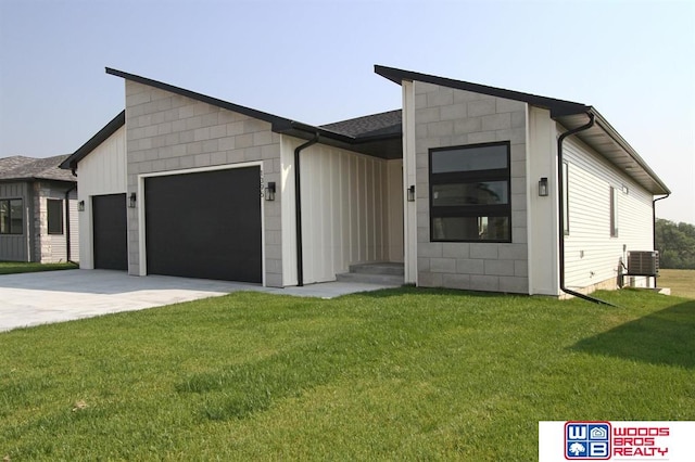 contemporary home featuring central AC unit, a garage, and a front lawn