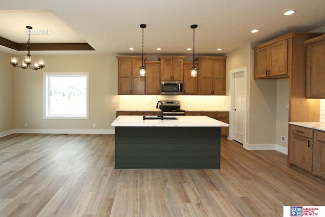 kitchen with pendant lighting, sink, stainless steel appliances, and a kitchen island with sink