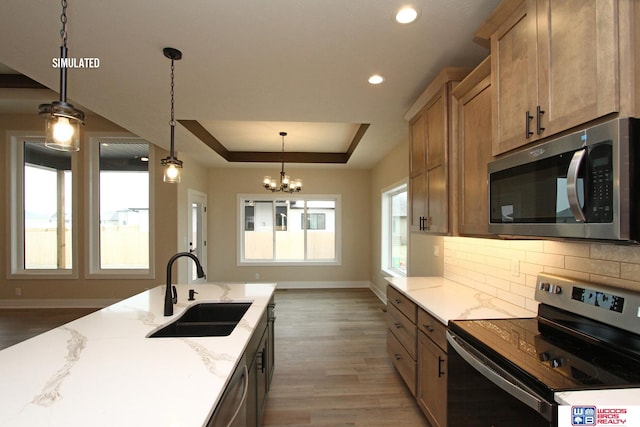 kitchen featuring pendant lighting, sink, dark hardwood / wood-style floors, light stone countertops, and appliances with stainless steel finishes