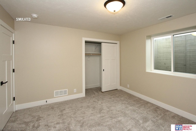 unfurnished bedroom with light carpet, a closet, and a textured ceiling