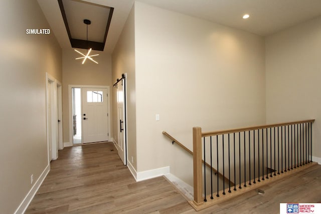 corridor featuring a high ceiling, an inviting chandelier, and light hardwood / wood-style flooring