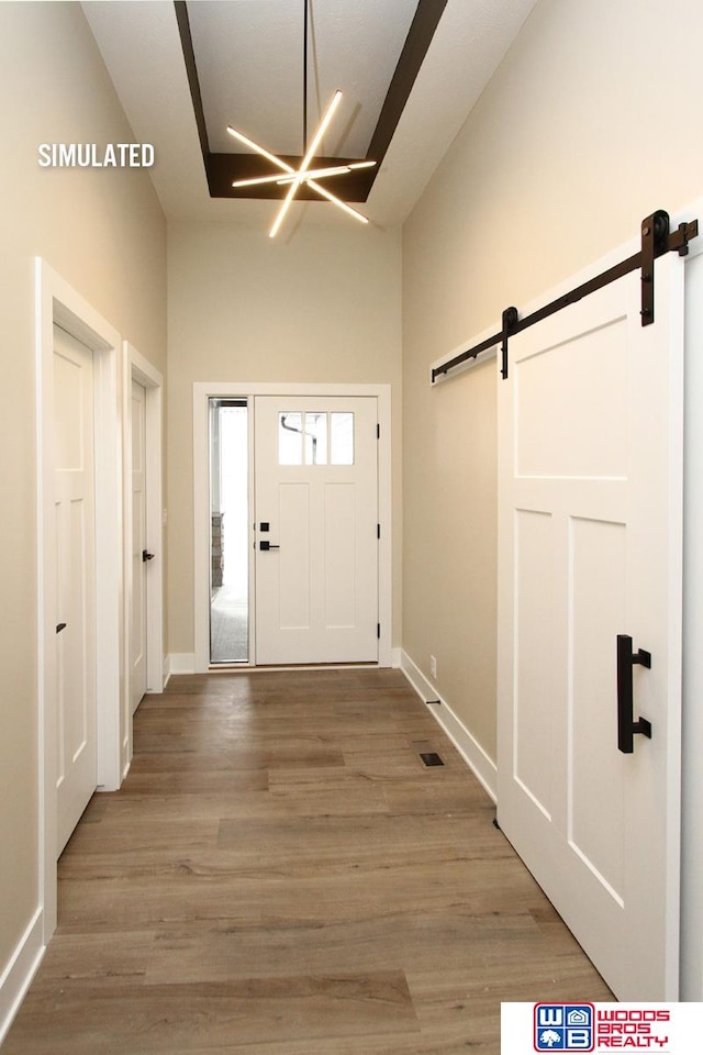 foyer entrance featuring a barn door, hardwood / wood-style floors, and a notable chandelier