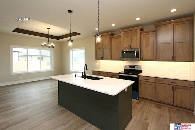 kitchen featuring sink, light hardwood / wood-style flooring, pendant lighting, a kitchen island with sink, and appliances with stainless steel finishes