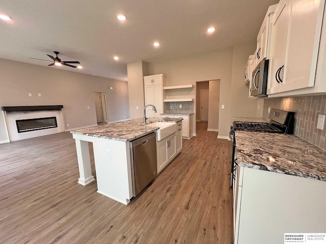 kitchen featuring appliances with stainless steel finishes, white cabinetry, a kitchen island with sink, and sink