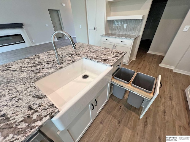 details with decorative backsplash, light hardwood / wood-style flooring, white cabinetry, and light stone counters