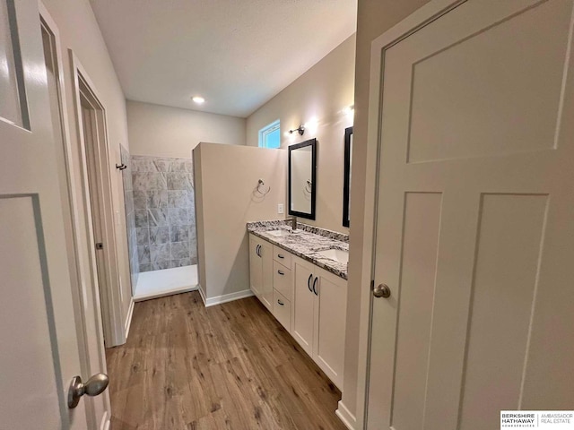 bathroom with a tile shower, vanity, and hardwood / wood-style flooring