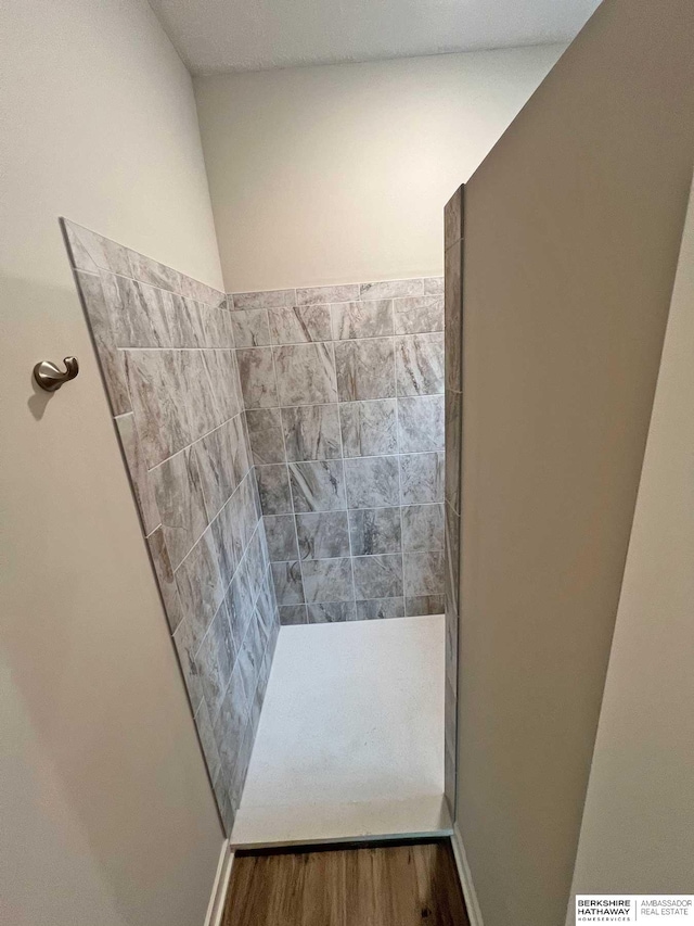 bathroom with tiled shower and hardwood / wood-style floors