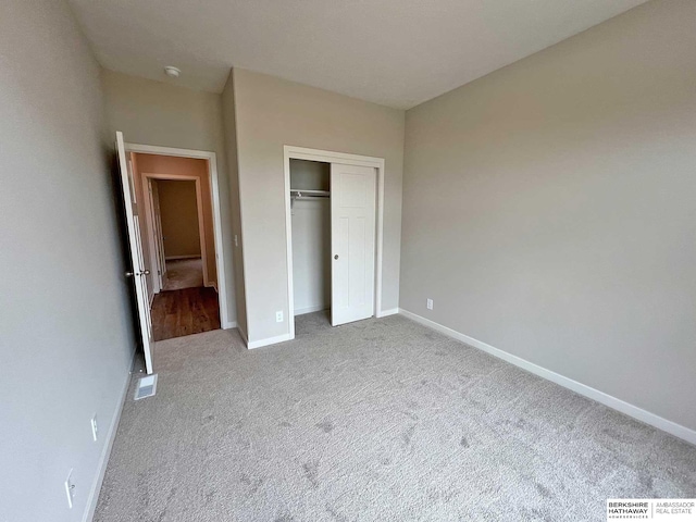 unfurnished bedroom with light colored carpet and a closet