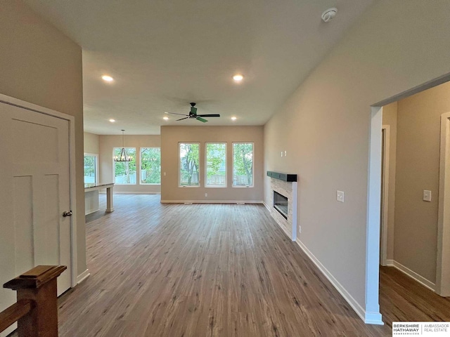 unfurnished living room with hardwood / wood-style floors and ceiling fan with notable chandelier