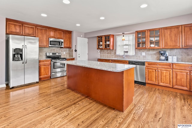 kitchen featuring light stone counters, a center island, light hardwood / wood-style floors, and appliances with stainless steel finishes