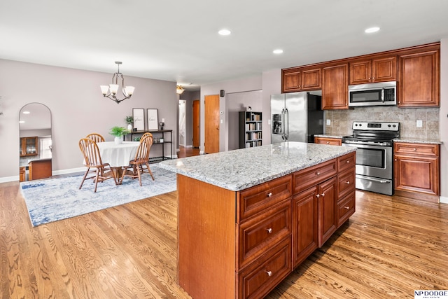 kitchen featuring stainless steel appliances, a kitchen island, and light hardwood / wood-style flooring