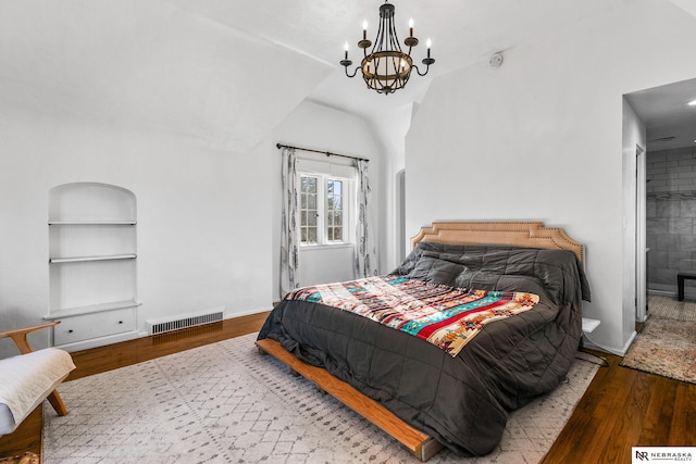 bedroom with light wood-type flooring, ensuite bathroom, lofted ceiling, and a notable chandelier