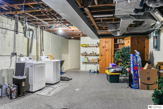 basement with washing machine and clothes dryer, electric panel, and wood walls