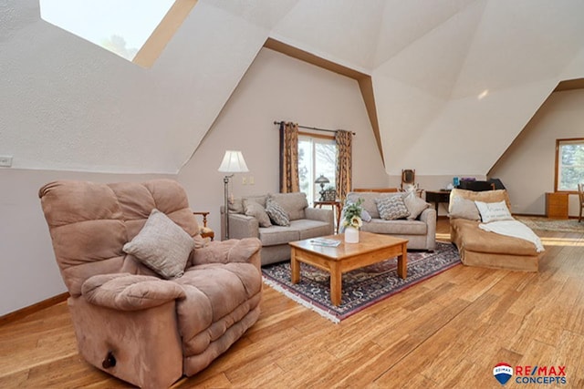 living room featuring vaulted ceiling with skylight and light hardwood / wood-style flooring