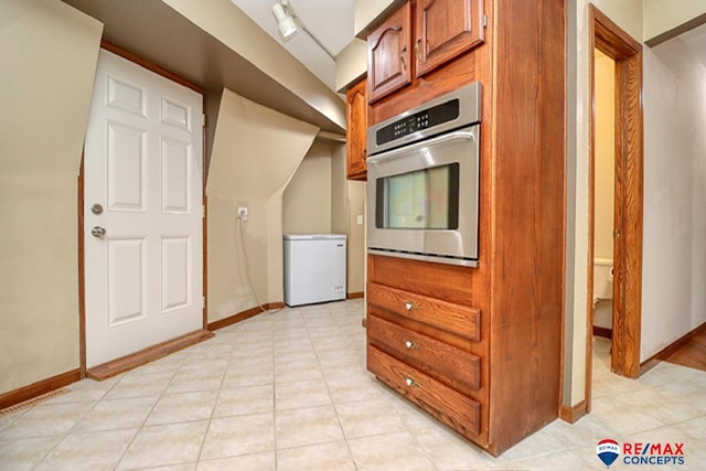 kitchen featuring stainless steel oven, light tile patterned floors, and white fridge