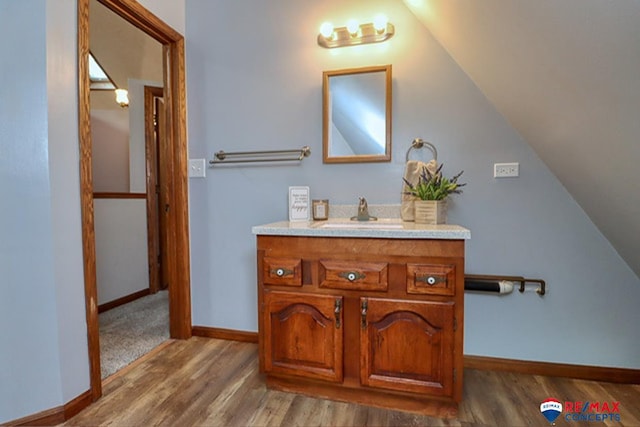 bathroom featuring hardwood / wood-style floors, vanity, and lofted ceiling