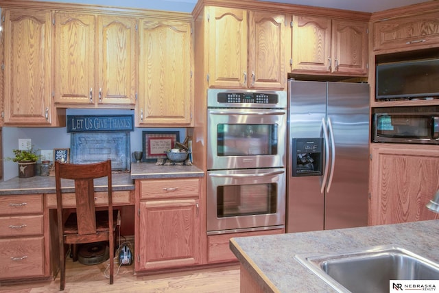 kitchen featuring light wood-type flooring, sink, and appliances with stainless steel finishes
