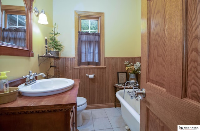 bathroom with a bathing tub, tile patterned floors, wood walls, toilet, and vanity