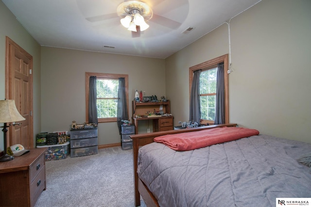 carpeted bedroom with multiple windows and ceiling fan