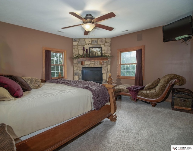 carpeted bedroom featuring ceiling fan, a fireplace, and multiple windows