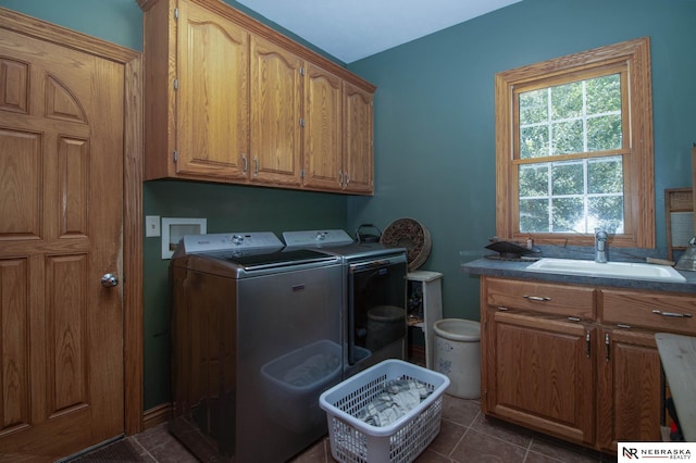 washroom with cabinets, dark tile patterned floors, sink, and washing machine and dryer