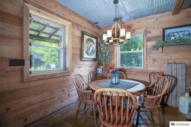 dining room with wood walls and a notable chandelier