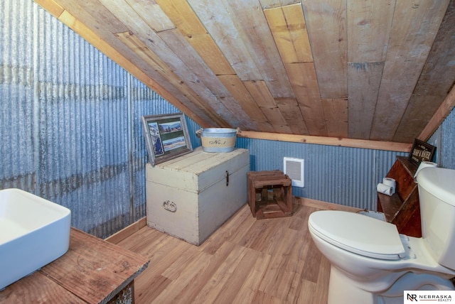 bathroom with wooden walls, wood-type flooring, wooden ceiling, toilet, and lofted ceiling